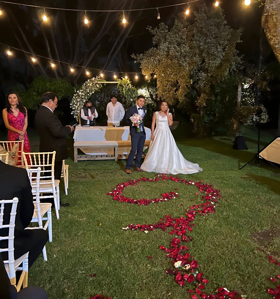Ceremonia de boda al aire libre, con pétalos sobre el césped y luces cálidas